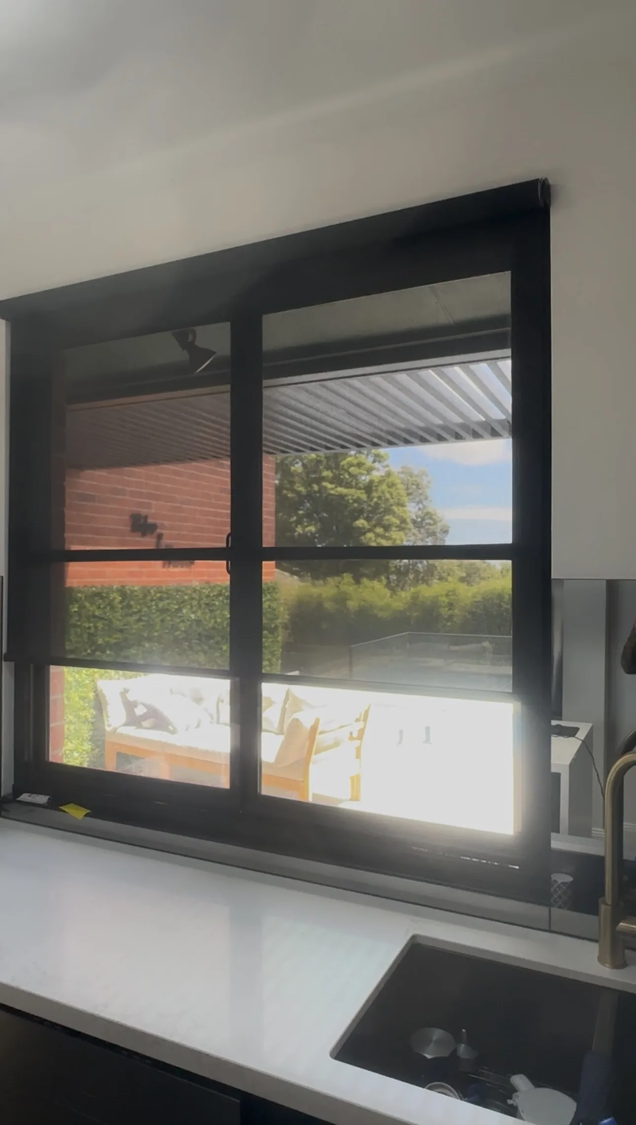 Sleek black motorised screen roller blinds installed in the kitchen and dining area to reduce glare, improve heat control and add privacy with a modern finish.