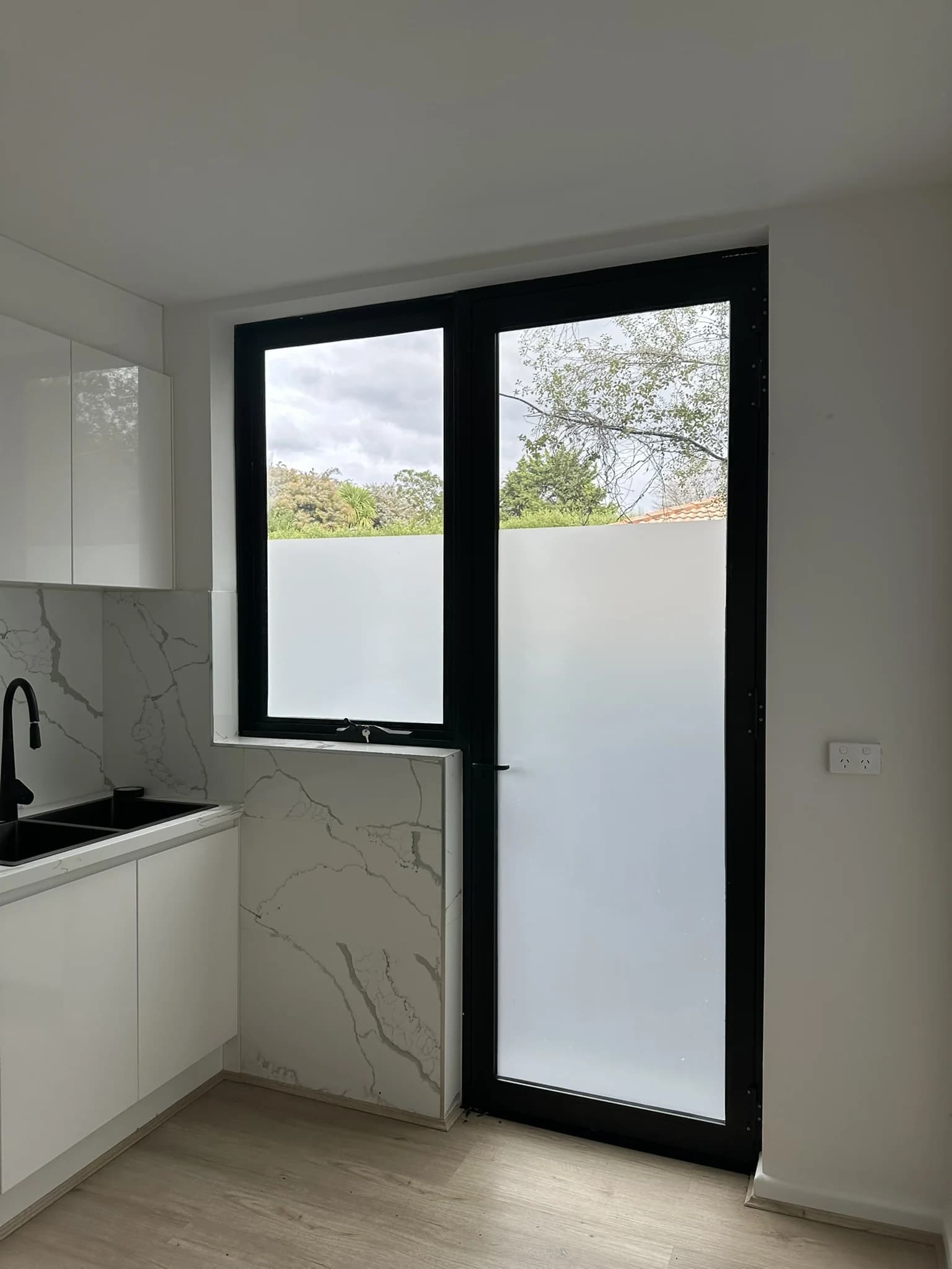 Frosted film applied to the rear kitchen door in a freshly renovated Kew East home. The door opens onto a narrow side path with a neighbouring fence close by, so the glass needed privacy without losing the light into the kitchen. Frosted film does both, and unlike a reflective film it holds that privacy after dark as well.