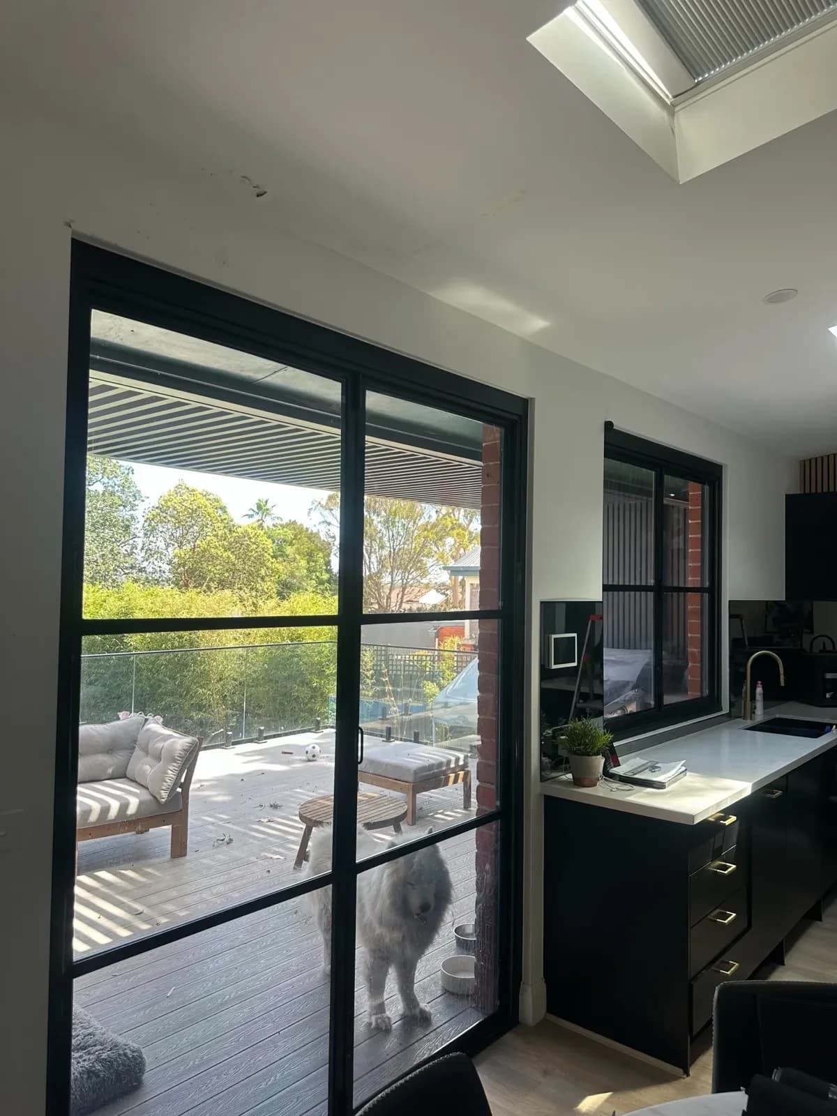 Roller blinds in a modern open-plan kitchen and living area with floor-to-ceiling glazing.