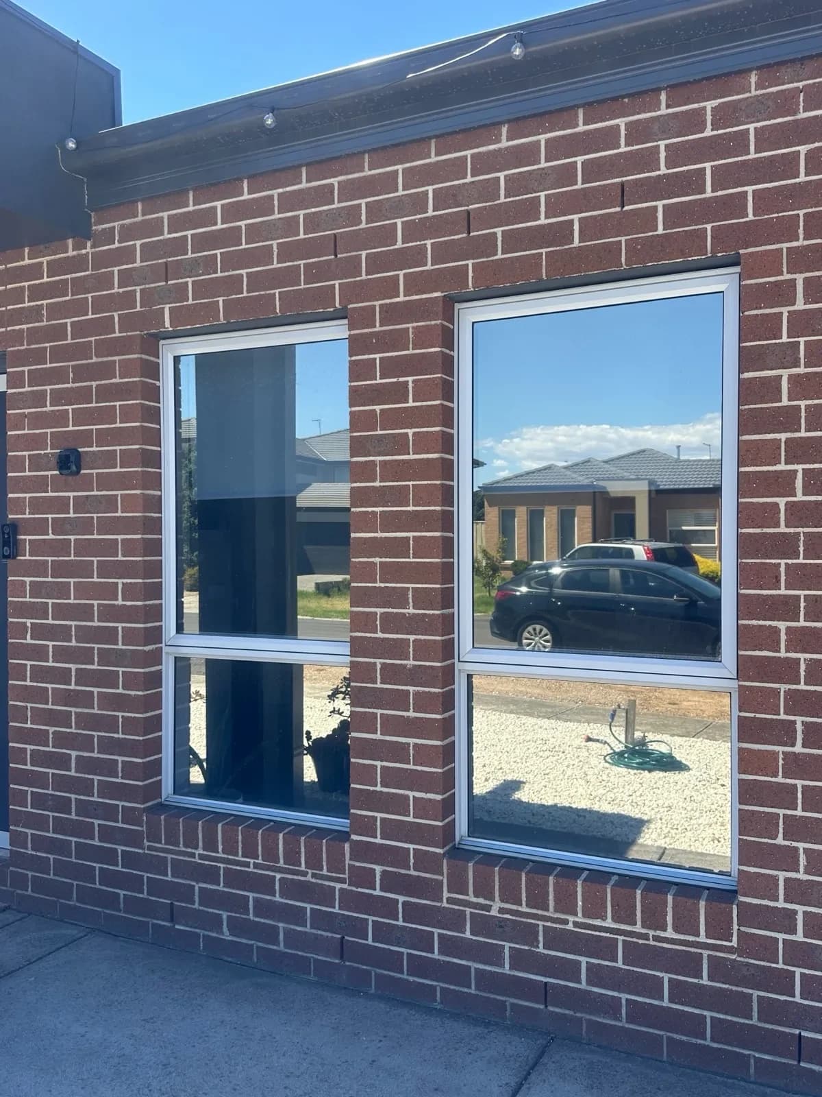 Solar tint on all outward-facing windows of a two-storey brown brick home. Before and after visible across six panes.