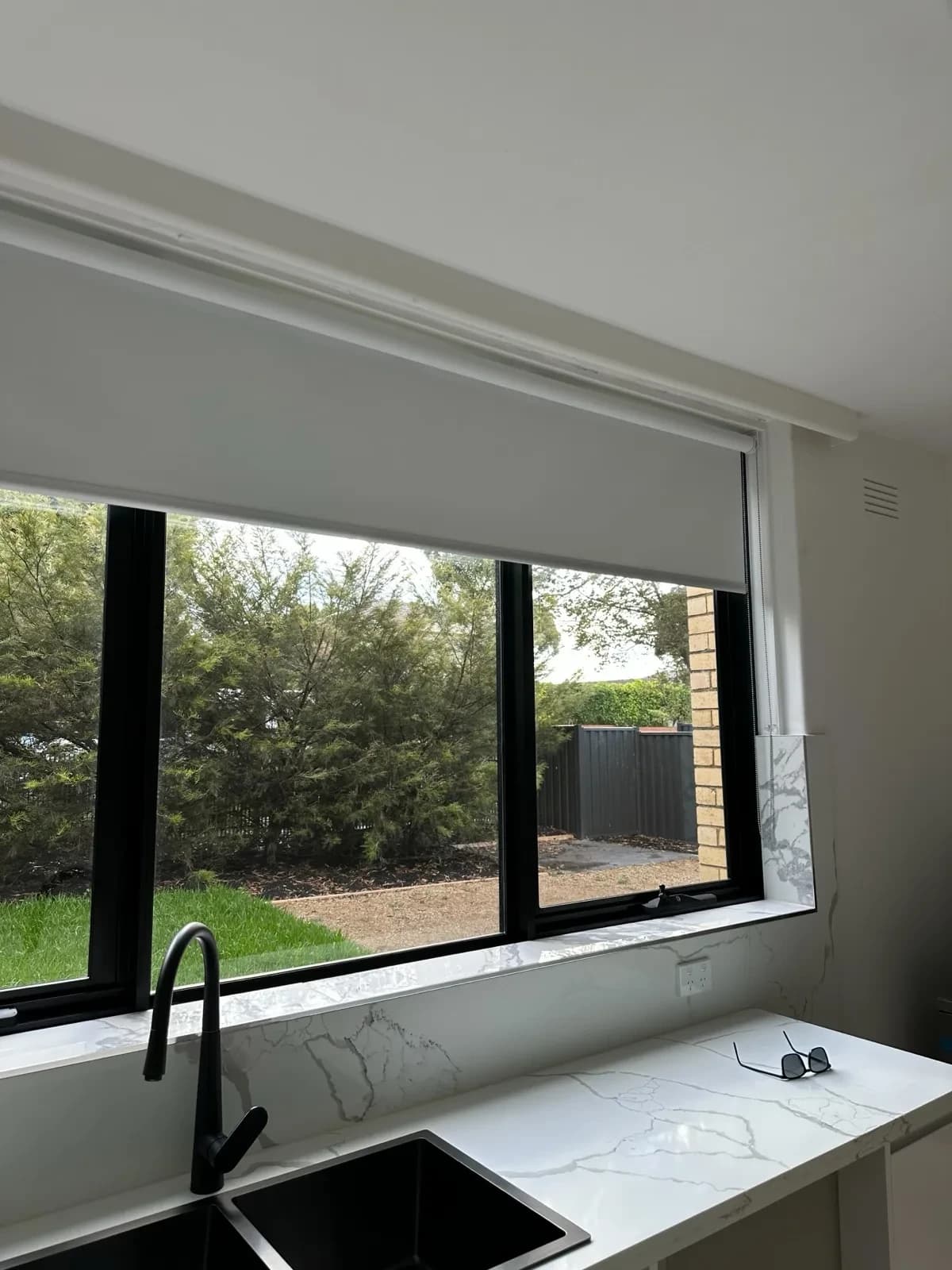 Solar tint on kitchen windows behind marble-look splashback, plus roller blind in hallway.